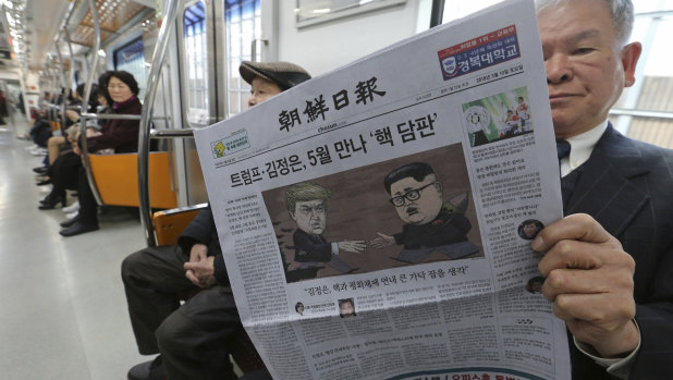 A passenger reads a newspaper with headline of a planned summit meeting between North Korean leader Kim Jong Un and U.S. President Donald Trump on a  subway train in Seoul, South Korea.