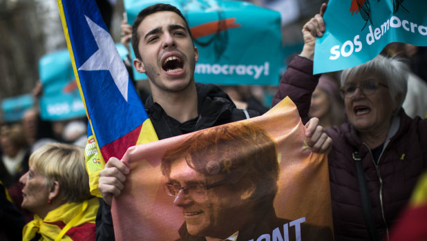 A demonstrator in Barcelona on Sunday holds a poster with a photo of Carles Puigdemont, the deposed leader of Catalonia's pro-independence party.