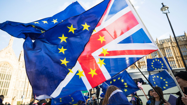 Brexit protesters wave flags made up of a European Union flags and British Union flags, otherwise known as a Union Jack, outside the Houses of Parliament in London.
