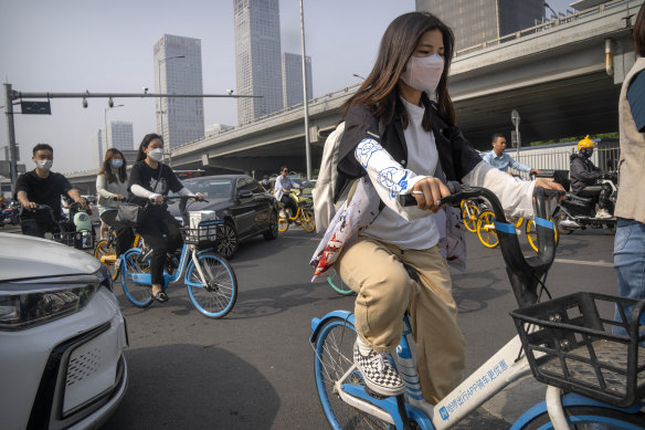 Commuters wearing face masks make their way along a street in the central business district during the morning rush hour in Beijing, 