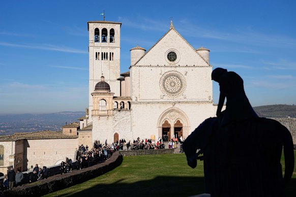 Los peregrinos abandonan la basílica en la ciudad de la colina de Umbría que el monje medieval hizo famosa.