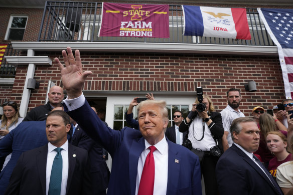 Former President Donald Trump waves to the crowd outside a fraternity house.