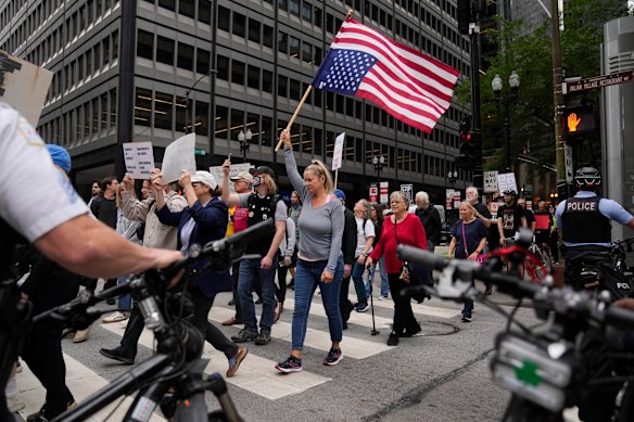 A protestor carries an upside-down American flag as she and other anti-Trump, anti-fascism demonstrators march in nationwide Good Trouble Lives On activities. 