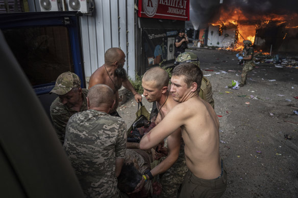 Ukrainian soldiers move to the ambulance an injured woman after a Russian rocket attack on a food market in the city center of Kostiantynivka, Ukraine.