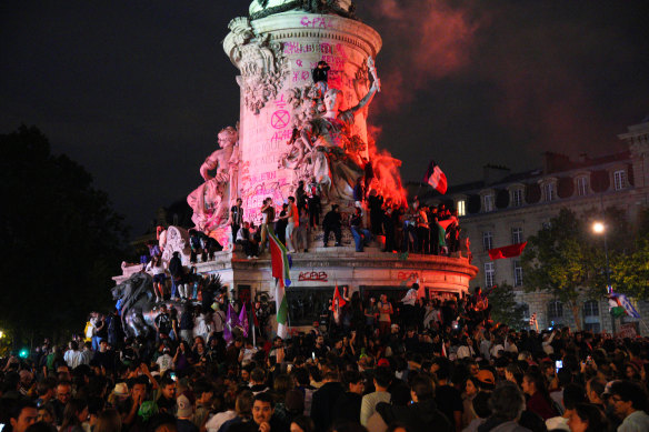 Demonstrators climb on the Monument a la Republique during a protest following the legislative election results.