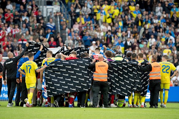 Danish and Ukrainian players escort Eriksen to the waiting ambulance.