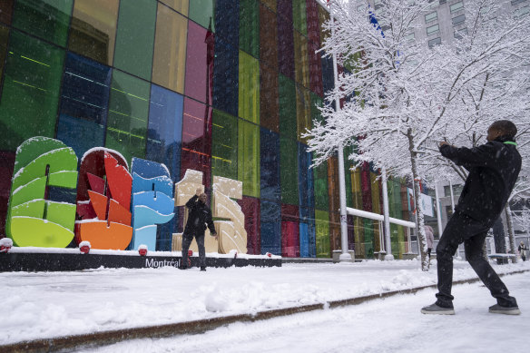 Delegates take souvenir photos during a snowfall outside the convention centre at the COP15 UN conference on biodiversity in Montreal, Canada.