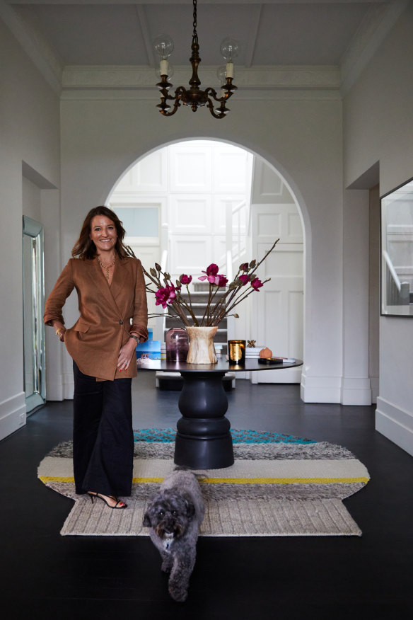 Lou with Lenny in the entrance hall. “The whole house was carpeted but we opted to sand back the original jarrah boards and stain them black,” says Lou. The table is by Moooi from Space Furniture and the rug is by Gan.