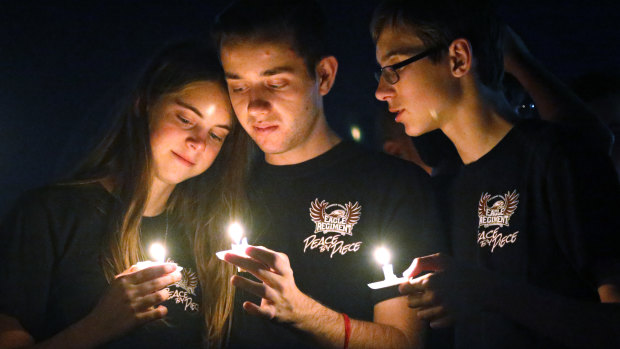 The latest slaughter: Attendees comfort each other at a candlelight vigil for the victims of the shooting at Marjory Stoneman Douglas High School.