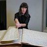 Curator Kate Rhodes with an original copy of The Age opened at the pages reporting on the Kelly Gang’s shootings.