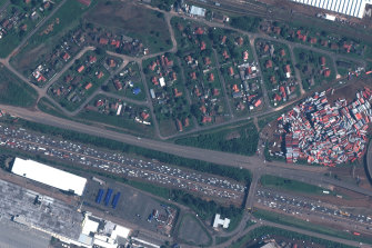 This satellite image provided by Maxar Technologies shows traffic jams and strewn shipping containers after the floods.