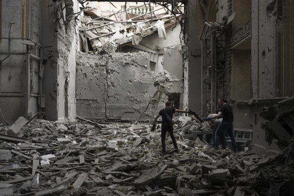 People stand on a mound of rubble while cleaning up inside the cathedral.