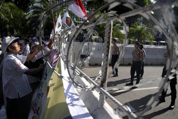 Protesters put up flags and posters on a razor wire barricade as police officers stand guard during a rally alleging a widespread fraud in the presidential election, outside the General Election Commission’s office in Jakarta, Indonesia, on Wednesday.