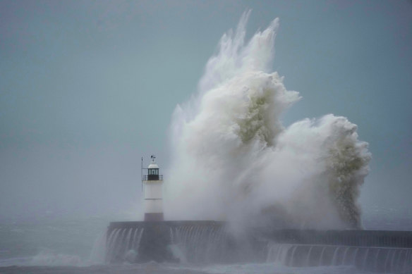 Waves crash over Newhaven Lighthouse and the harbour wall in Newhaven, southern England.