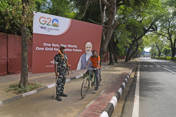 A para-military force soldier stands guard in front of a G20 banner with the photograph of Indian prime minister Narendra Modi. 