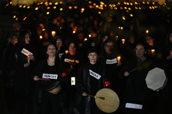 Women’s rights activists hold signs saying “never again” during a vigil in Santiago, Chile, on Sunday, for the victims of the dictatorship of General Augusto Pinochet.