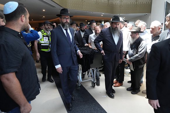 The coffin of Rabbi Eli Schlanger, a victim in the Bondi Beach mass shooting, is escorted out of a synagogue after his funeral service in Bondi.