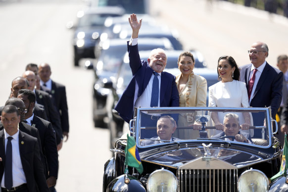 President-elect Luiz Inacio Lula da Silva, left, his wife Rosangela Silva, second from left smile from an open car after departing from the Metropolitan Cathedral to Congress for their swearing-in ceremony, in Brasilia.