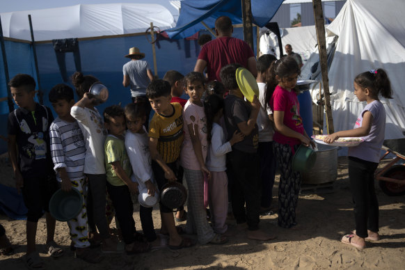 Palestinian children wait in line for a food distribution in a displaced tent camp, in Khan Younis, southern Gaza Strip.
