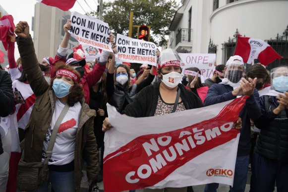 Supporters of presidential candidate Keiko Fujimori hold a banner reading “No to communism” and “fraud”, outside the official vote council office, in Lima.