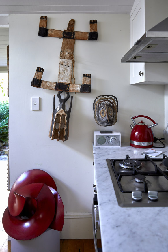 In the single-wall kitchen, a late 18th century African timber head mask is on the wall, and a metal sculpture by Russell McQuilty sits on the wooden floor.