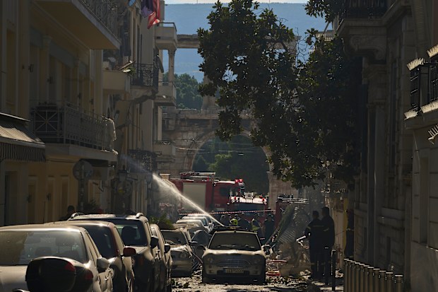 Firefighters work at the scene following a powerful blast that caused a building to collapse and injured at least two people in Athens’ Plaka district, with the ancient Hadrian’s Arch in the background, Friday, Sept. 25, 2026
