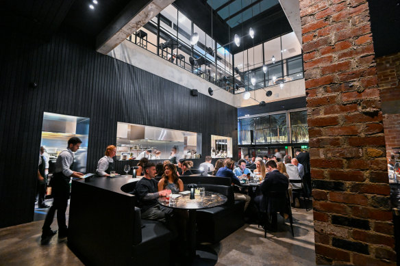 A glass walkway overlooks the atrium dining room’s interlocking leather booths.