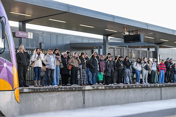 Commuters wait on the platform during the morning peak hour at Tarneit train station.