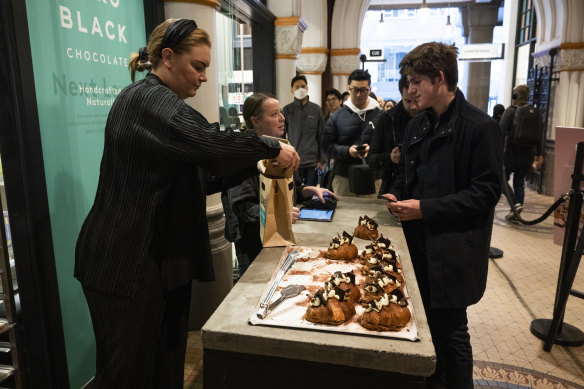 A man buys a croissant after making it to the front of a very long queue.