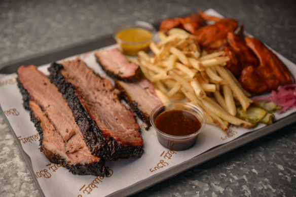 A tray of beef brisket, pork belly and fries and hot wings.