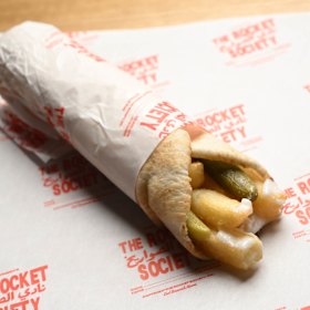 A wrap filled with hot chips, toum (garlic sauce) and pickles.