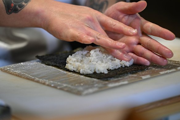 To make sushi rolls, take a half sheet of nori and press rice on top.