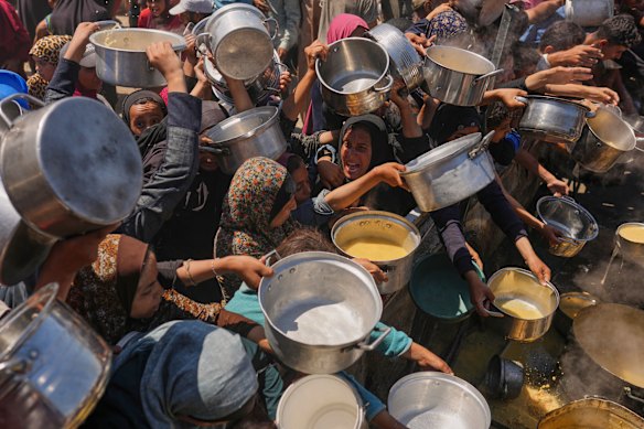 Palestinians struggle to get donated food at a community kitchen in Gaza City, northern Gaza Strip.