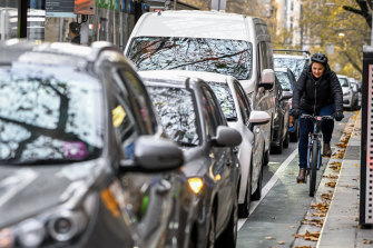 Cyclists make their way along a narrow bike lane along Collins Street. 