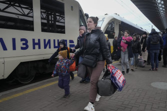 Parents accompany children and teenagers as they board a train after leaving Kyiv’s Central Children’s Hospital, following its evacuation.