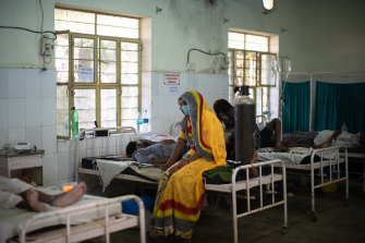 An Indian relative sits with a patient being treated for coronavirus in a  hospital in Rajasthan during the COVID wave in May. 