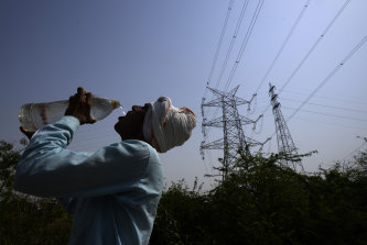 Seorang pekerja memuaskan dahaganya bekerja di luar pada hari yang bersuhu 45 derajat di Delhi.