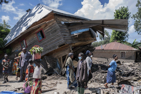 People walk next to a house destroyed by the floods in the village of Nyamukubi, South Kivu province, in Congo.