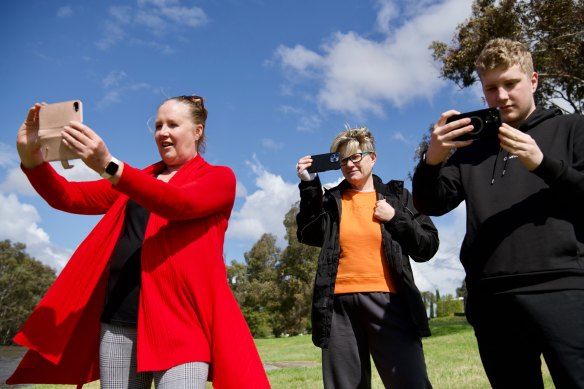 Locals take photos of the water surge along the Werribee River trail.