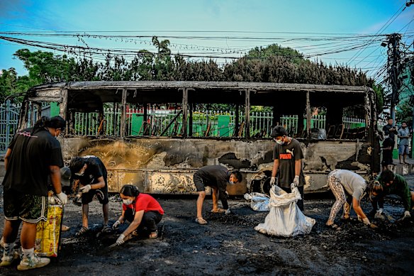 Os jovens limpam as cinzas de uma rua em torno de um ônibus que foi queimado durante dias de tumultos e revoltas políticas, em Katmandu.