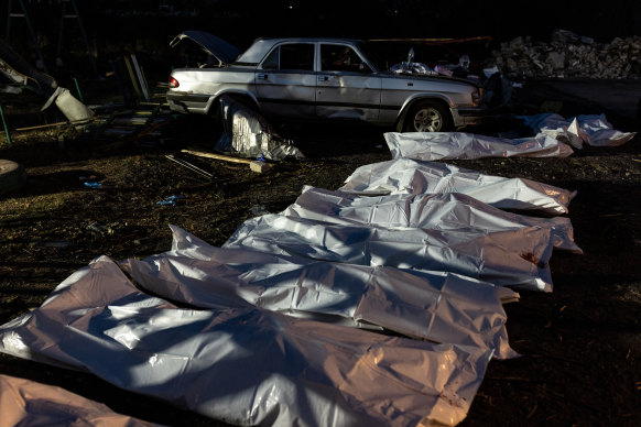 Dead bodies lie on the ground outside of a destroyed village shop and café in Hroza, Ukraine. 