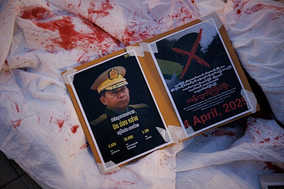 Thai protesters lay posters condemning Myanmar General Min Aung Hlaing on top of a sheet covered in fake blood in Bangkok, Thailand.