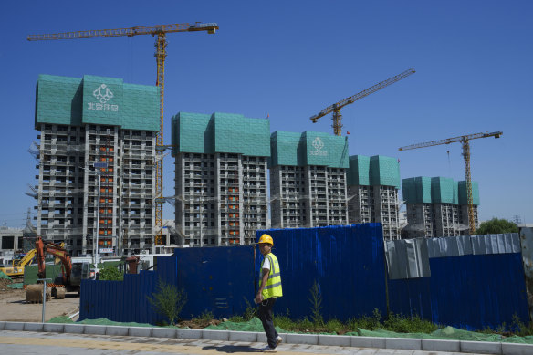 A construction worker walks past a housing project under construction on the outskirts of Beijing, China, on Wednesday. There are millions of unsold, unfinished and vacant homes across China due to the property market collapse.  