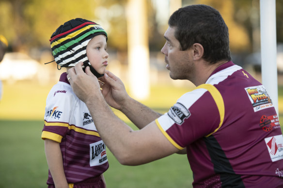 Sean Buchanan adjusts the headgear on his son Beau, who plays for the Glenmore Park Brumbies in the Penrith Junior Rugby League.