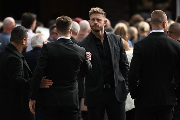 Essendon player Jayden Laverde (facing camera) greets a friend before Hannah McGuire’s funeral.