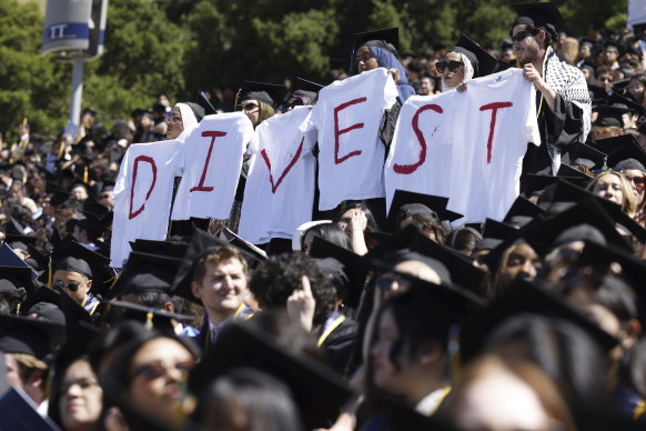 Pro-Palestinian students hold white t-shirts stating the message, “DIVEST,” as they protest during the UC Berkeley graduation at California Memorial Stadium in Berkeley, California.