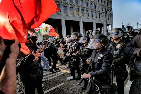 Los Angeles police in riot gear form a skirmish line and push protesters down a street away from a federal building in downtown Los Angeles on Monday.