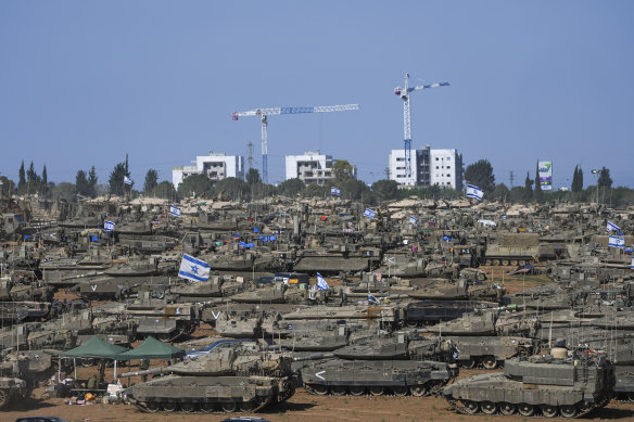 Israeli soldiers work on armoured military vehicles at a staging ground near the Israeli-Gaza border, in southern Israel.