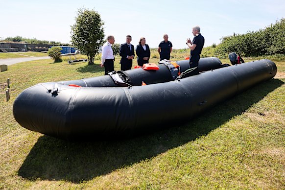 British Prime Minister Andy Burnham (second from left) stands by a recovered small boat, which was used by migrants crossing the English Channel.