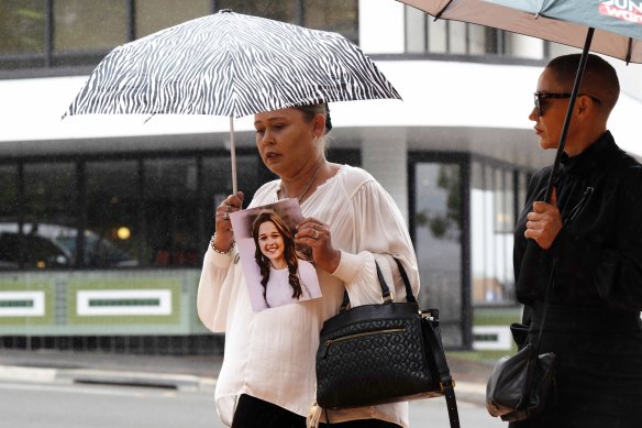 Gabby McLennan’s mother holds a photo of her daughter as she walks into court.